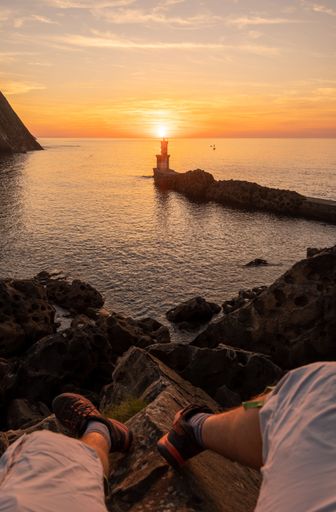 A vertical POV of a person on a rocky shore looking at sunset in San Juan, Gipuzkoa, Basque Country