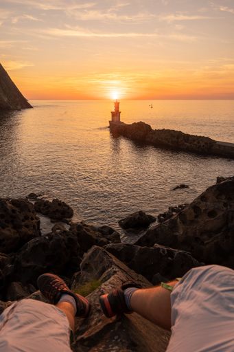 A vertical POV of a person on a rocky shore looking at sunset in San Juan, Gipuzkoa, Basque Country