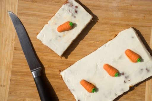 A top view of a knife next to a vegan carrot cake, on a wooden table
