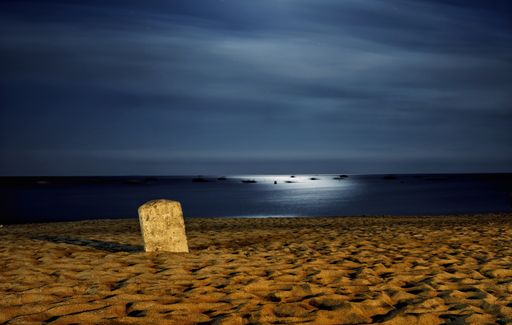 A beautiful shot of a sandy seashore with the sea on the background at night