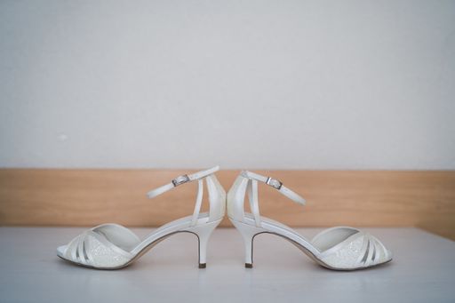 A close up shot of white wedding sandals in a blurry background