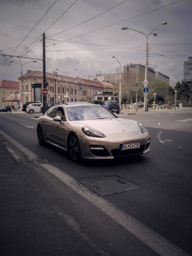 A vertical shot of a Porsche driving in the street in Vienna, Austria