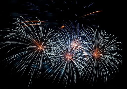 Rays of festive fireworks against the background of the night black sky. Pyrotechnics.