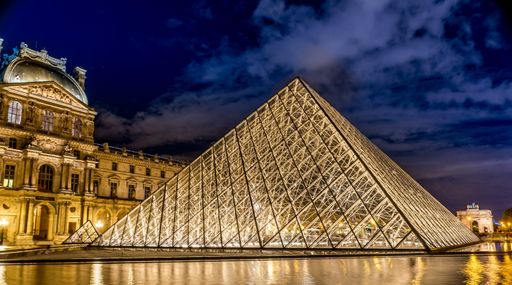 A horizontal shot of the beautiful Louvre museum at night time in Paris, France