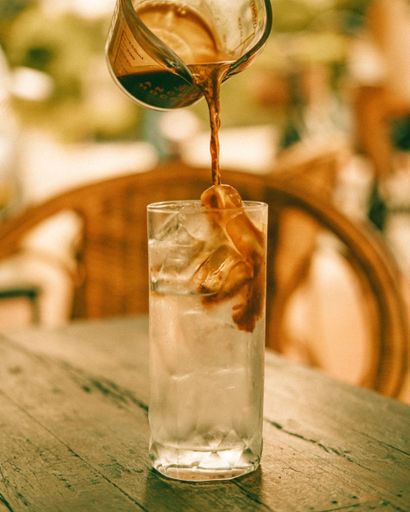 A shallow focus shot of Coffee being poured in to water on the table