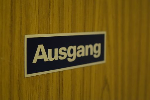 German sticker 'Ausgang' (exit) on a rustic 70ies veneered door, spatial illusion by focus on letters A and u
