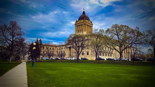 The beautiful Manitoba Legislative building with a green park and cars in front in Winnipeg, Canada