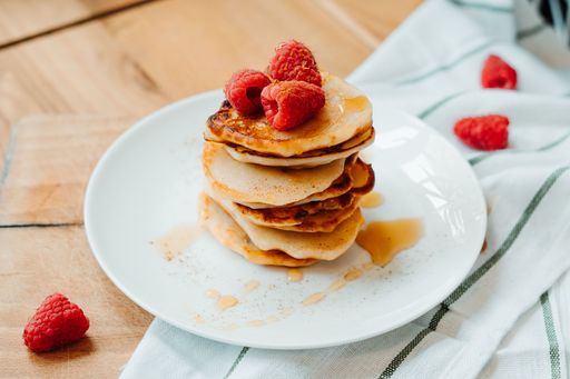 Pancakes with raspberries and maple syrup, lying on the table, stacking