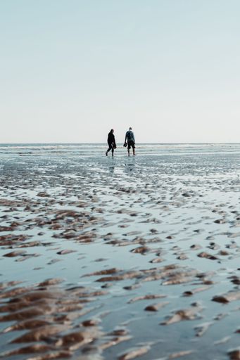Random people walking at the wet beach by the England's east cost