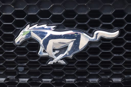 A closeup shot of the logo on the radiator grille of a Ford Mustang