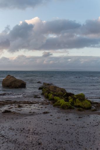 A beautiful view of a rocky shore of a sea under the blue cloudy sky