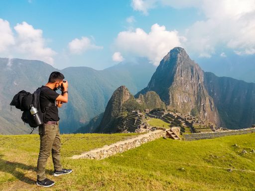 A beautiful view of a man taking photos with his camera of a green mountain peak