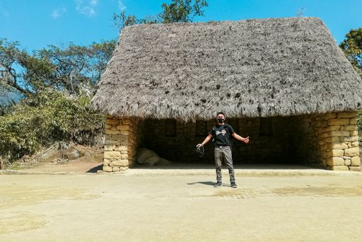 A travelling photographer posing in the background of traditional hut