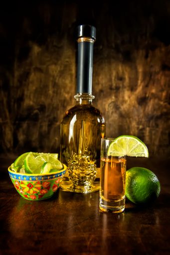 Image of a tequila bottle, shot with lime and lime wedge
