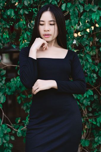 A vertical shot of a young Southeast Asian female in a black dress