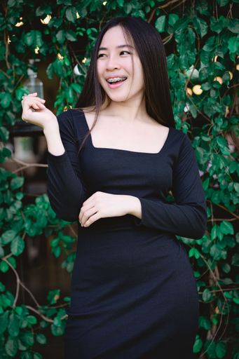 A vertical shot of a young happy Southeast Asian female in a black dress