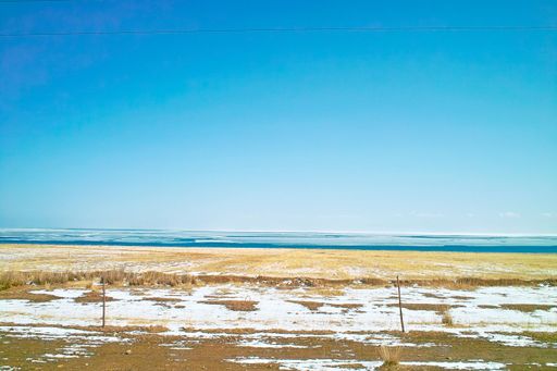 A snowy field near the sea under a clear cloudless sky