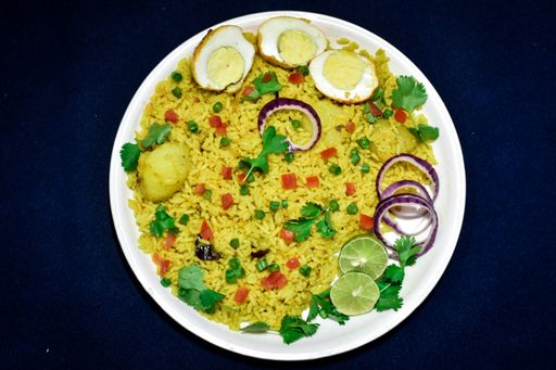 A high angle shot of yellow rice with eggs, onion, and lime