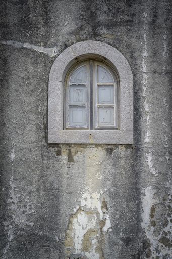 A vertical shot of a small window of an old building under the lights