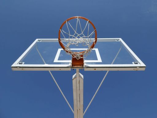 Basketball hoop with net on an outdoor court with sky background, view from below