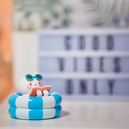 A vertical shot of a funny Pop Mart Bobo and Coco figurine in a pool reading a book