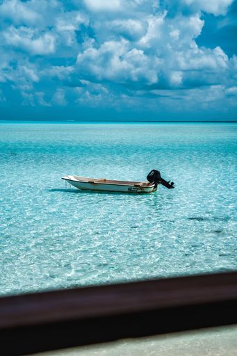 A vertical shot of a boat floating on a clear blue sea under a bright sky