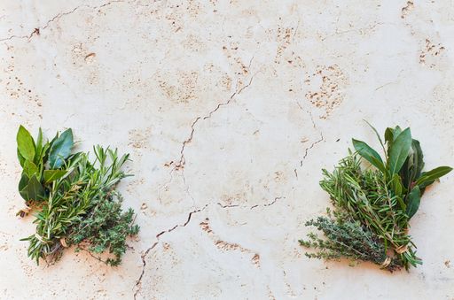An overhead shot of fresh herbs on cracked concrete surface with space for your text