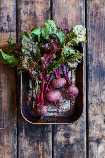 An overhead shot of fresh organic beetroot on a tray against a wooden surface