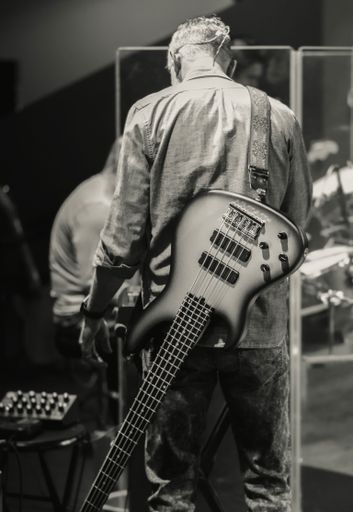 A grayscale of a musician with guitar from behind
