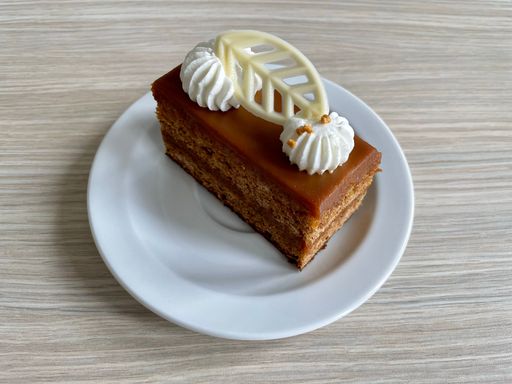 A closeup shot of a Toffee cake with a white chocolate decoration on a white plate