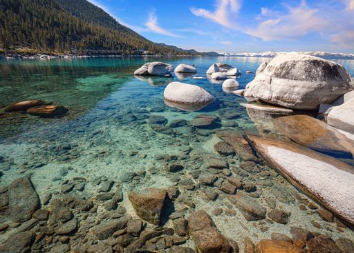 The rocky sea by the hill under the blue sky with clouds