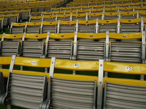 Patterns of yellow plastic chairs of an empty stadium with no one around