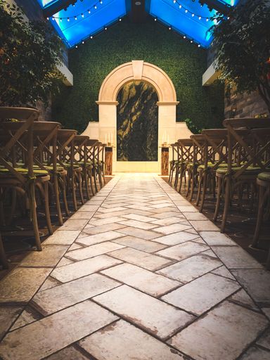A scenic hot of a wedding venue with wooden chairs and an illuminated arch