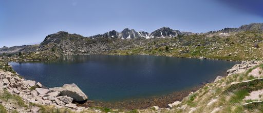 A panoramic shot of a lake between the hills captured on a sunny day