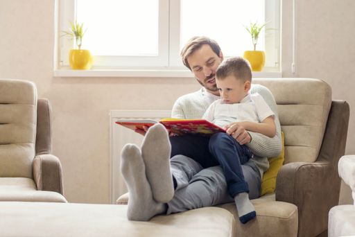 A shallow focus shot of a father reading a children's book for his son