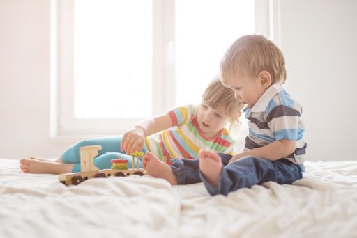 A brother and a sister playing on the bed in the bedroom