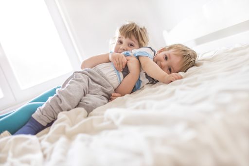 A brother and a sister playing on the bed in the bedroom