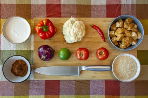 A high angle shot of the various vegetables  on a wooden board with sauces in the bowls