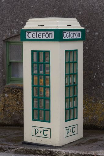 A vertical shot of a white and green telephone cabin booth on a street in Ireland, United Kingdom