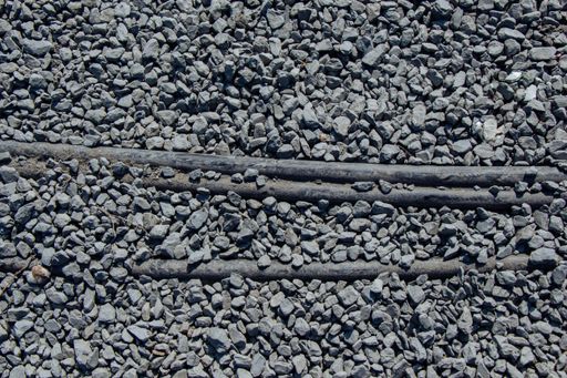 An overhead shot of a gravel surface with exposed pipes