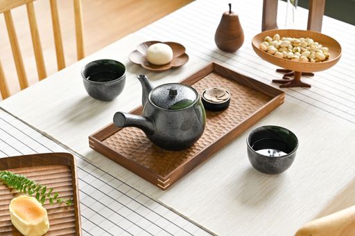 A closeup shot of a kettle of tea and pistachios on the table