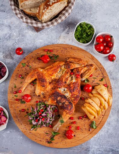 A vertical shot of a fried whole chicken with different side dishes