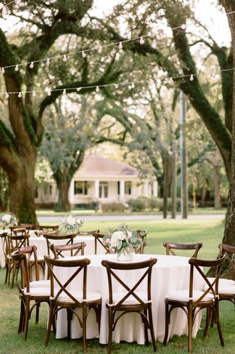 A selective focus shot of wedding tables decorated with flower bouquets in the park under the trees