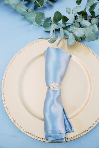 A top view shot of a ceramic white plate on blue surface with a napkin on a wedding table
