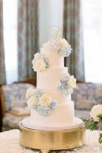 A selective focus shot of a stunning white wedding cake decorated with flowers on the table