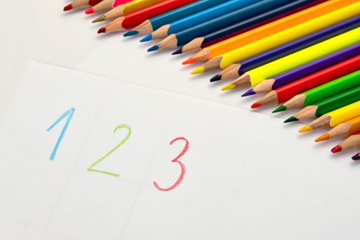 A closeup shot of colored pencils and letters on a white paper, Learning colors and letters