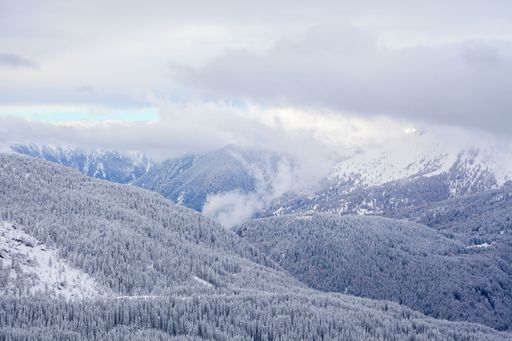 A aerial shot of a valley in the alps with clouds above