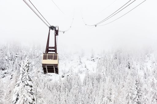 A cable car in a snowy landscape above a forest