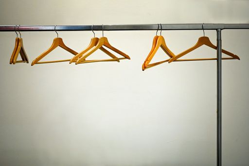 A deserted cloakroom view with clothes rack and wooden hangers on white wall