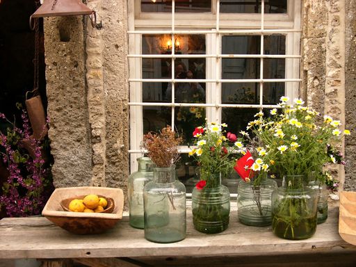 The flowers and Turkish flag in glass vases in front of the window of an old building in Alacati